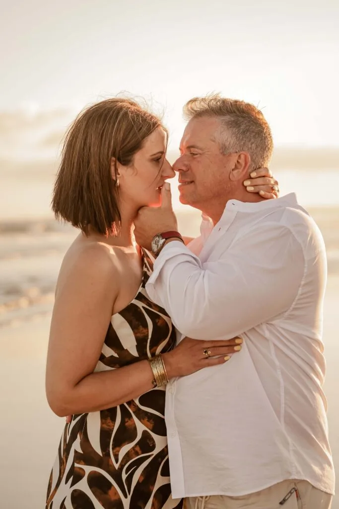 Couple embracing on the beach at golden hour during a couple photoshoot