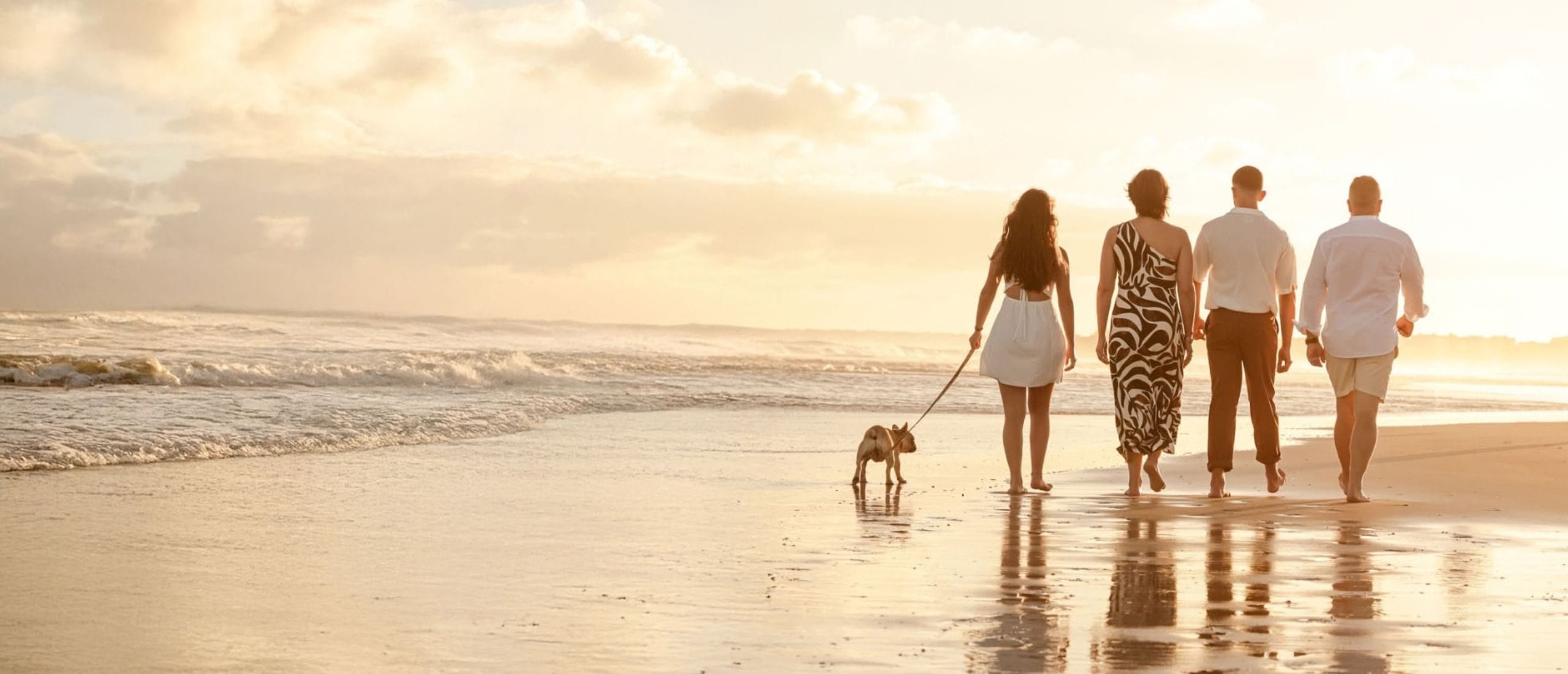 Family walking barefoot along the beach with their dog at golden hour during a family photoshoot on the Eastern Cape coast by Adri Krige Photography